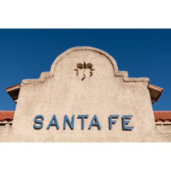 Photograph of the top facade of an adobe building with a sign that reads SANTA FE