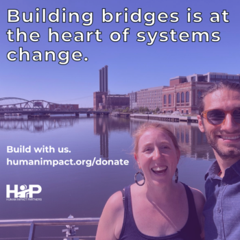 Photo of HIP’s “Bridging Strategies” staff smiling in front of a bridge over a river with white text reading “Building bridges is at the heart of systems change.”